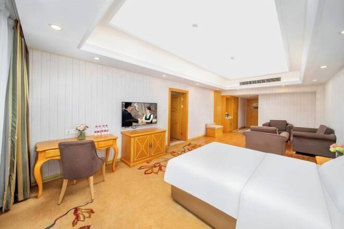 Une chambre d’hôtel comprenant un lit, un bureau avec une chaise, une télévision et un canapé.