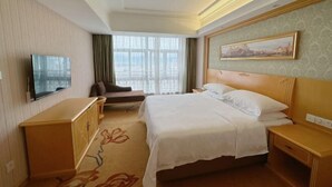 A hotel room with a bed, a TV, a desk, and a window with curtains. - Vienna Hotel (Lingshan Liufengshan Pedestrian Street) (Lingshan)
