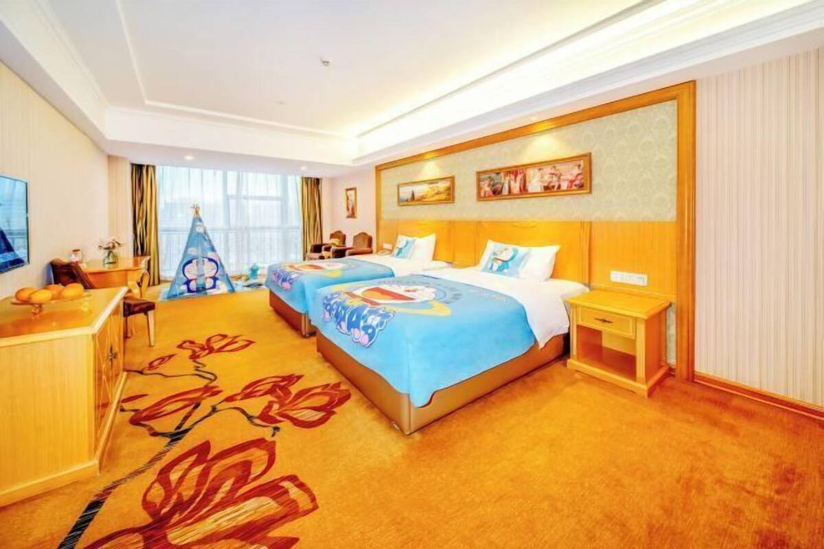 Une chambre d’hôtel avec deux lits, un bureau, une chaise, une petite table et un téléviseur.