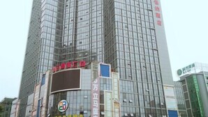 A tall, modern building with reflective glass windows and multiple signs in a foreign language. - Vienna Hotel (Lingshan Liufengshan Pedestrian Street) (Lingshan)