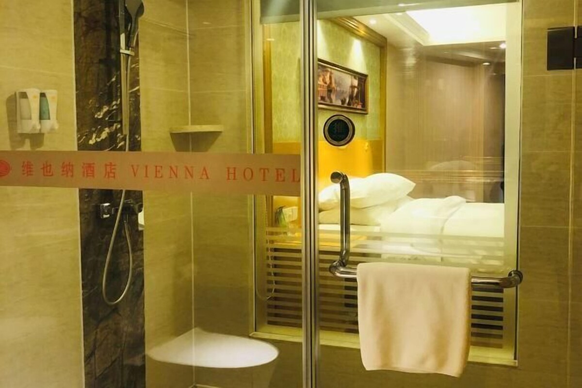 A hotel bathroom with a glass shower enclosure, a white sink, and a towel rack.