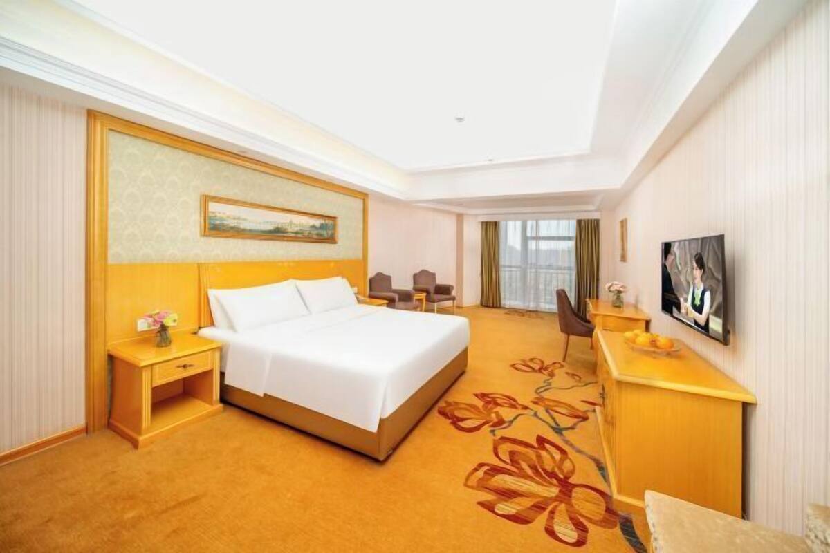 Une chambre d’hôtel avec un lit, un bureau, une chaise, une télévision et un tableau au mur.