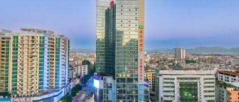 Un edificio de gran altura con fachada moderna de vidrio, rodeado de otros edificios y una calle concurrida.
