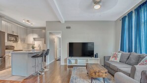 Ein modernes Wohnzimmer mit grauem Sofa, einem Holztisch und einem Flachbildfernseher.