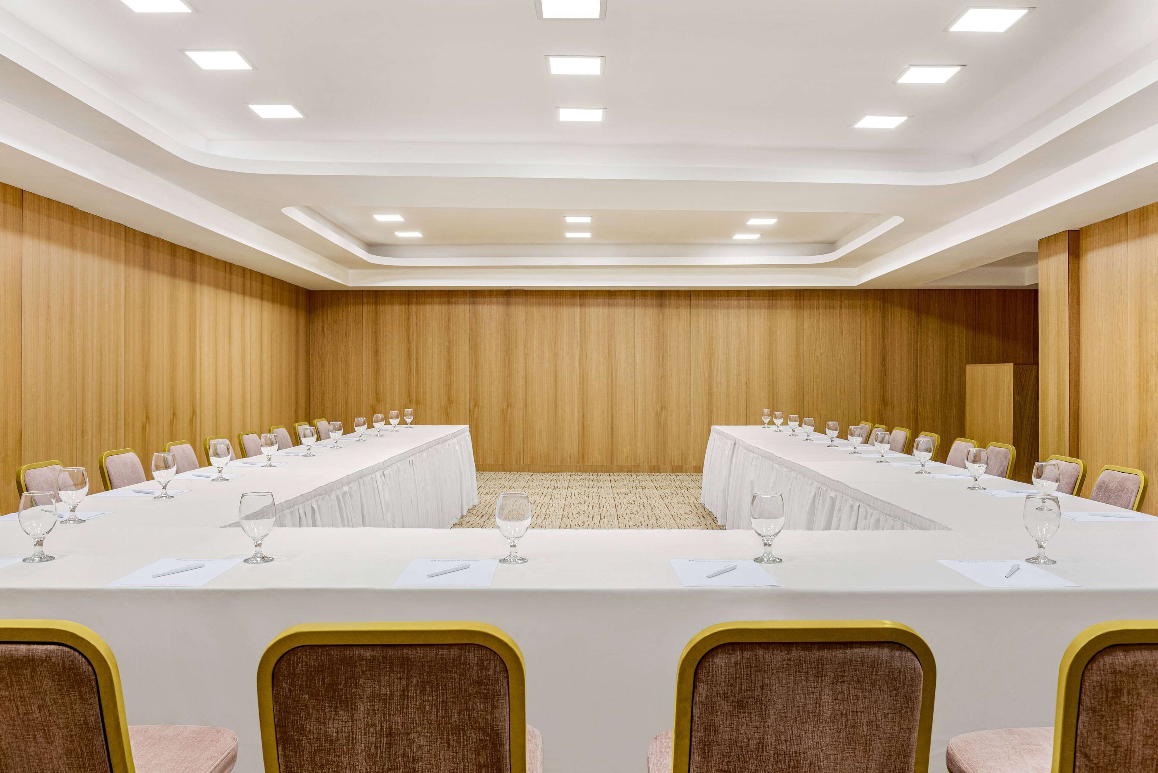 A conference room with a long table, chairs, and a carpeted floor.