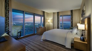 A hotel room with a large bed, a desk, a chair, and a TV.