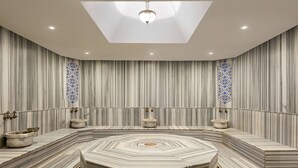 A modern bathroom with a central hexagonal marble sink, striped wallpaper, and decorative glass panels.
