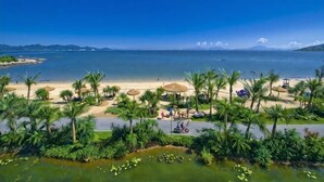 A beach with palm trees, a clear sky, and a calm sea. - Huidong Biguiyuan Shili Silver Beach Ocean Star Scenic Resort Apartment (Huidong)