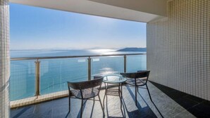 A balcony with a glass railing, two wicker chairs, and a small table. - Huidong Biguiyuan Shili Silver Beach Ocean Star Scenic Resort Apartment (Huidong)