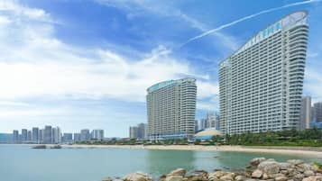 A beachfront hotel with a curved facade, multiple balconies, and a view of the ocean.