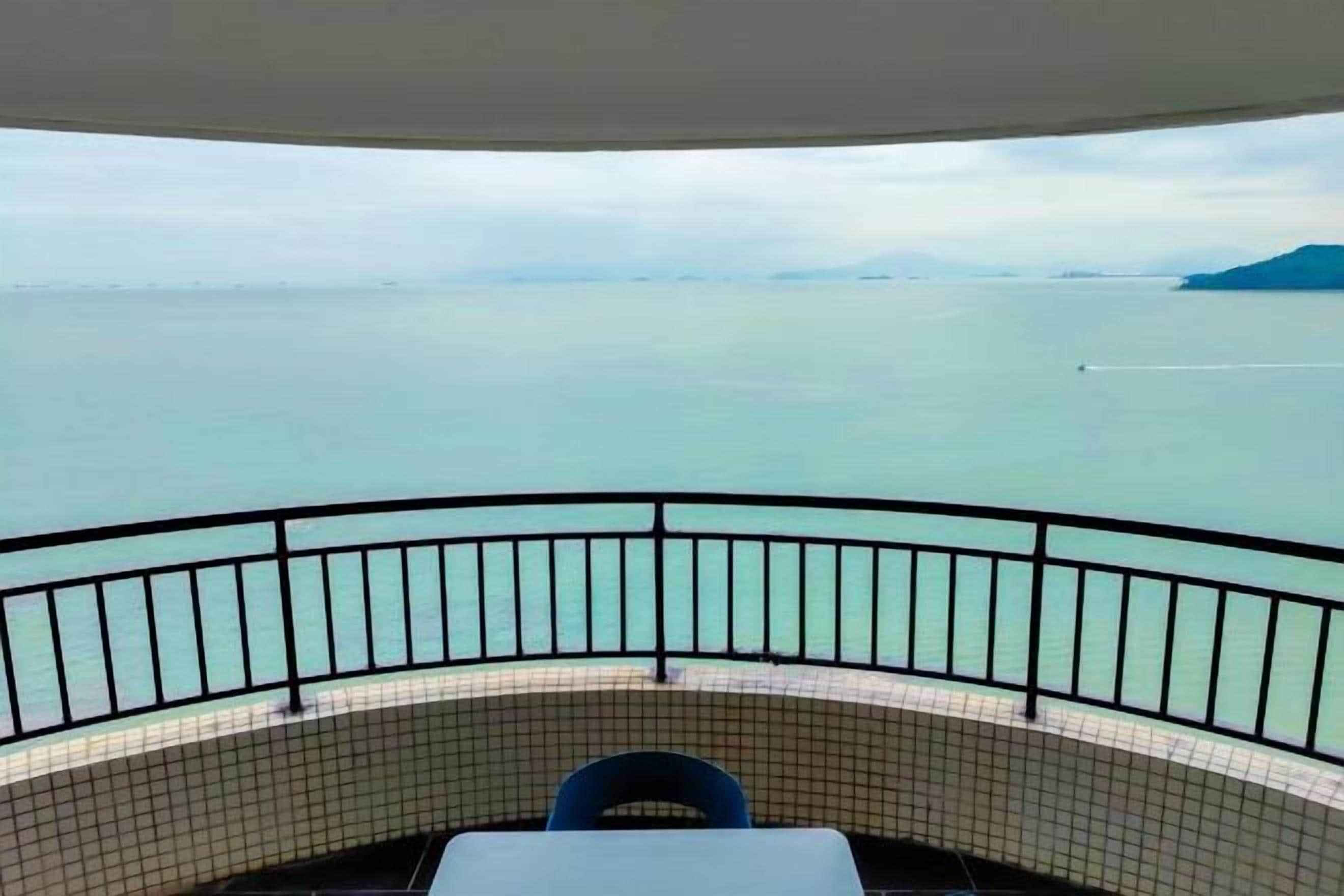 Un balcon avec vue sur la mer, une table et une chaise.