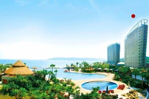 Un resort con una piscina grande, palmeras y edificios modernos.