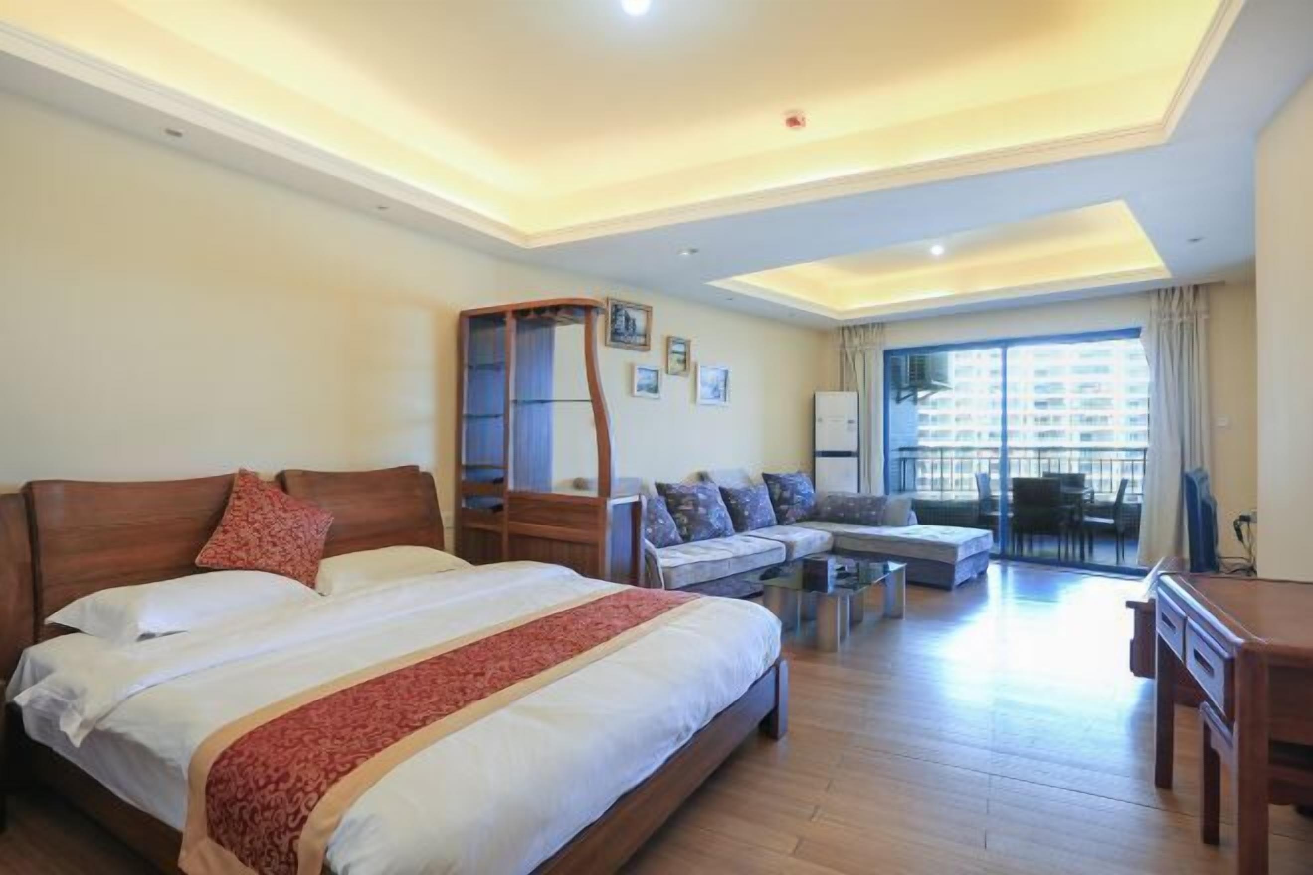 A hotel room with a large bed, a sofa, a desk, and a balcony with a view.
