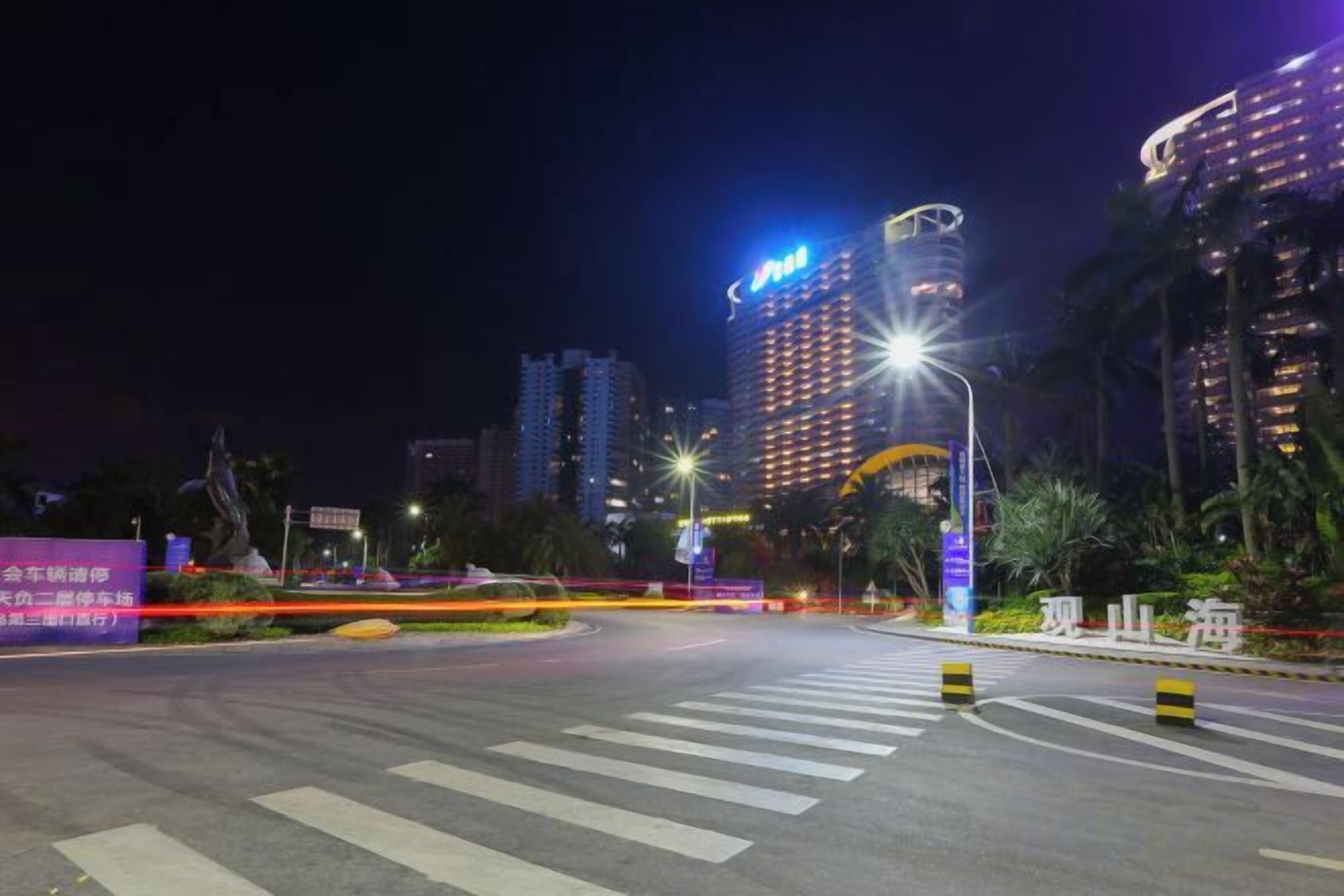 Paisagem urbana noturna com edifícios iluminados e uma faixa de pedestres.