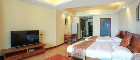 A hotel room with a TV, a wooden bed, a desk, and a chair.