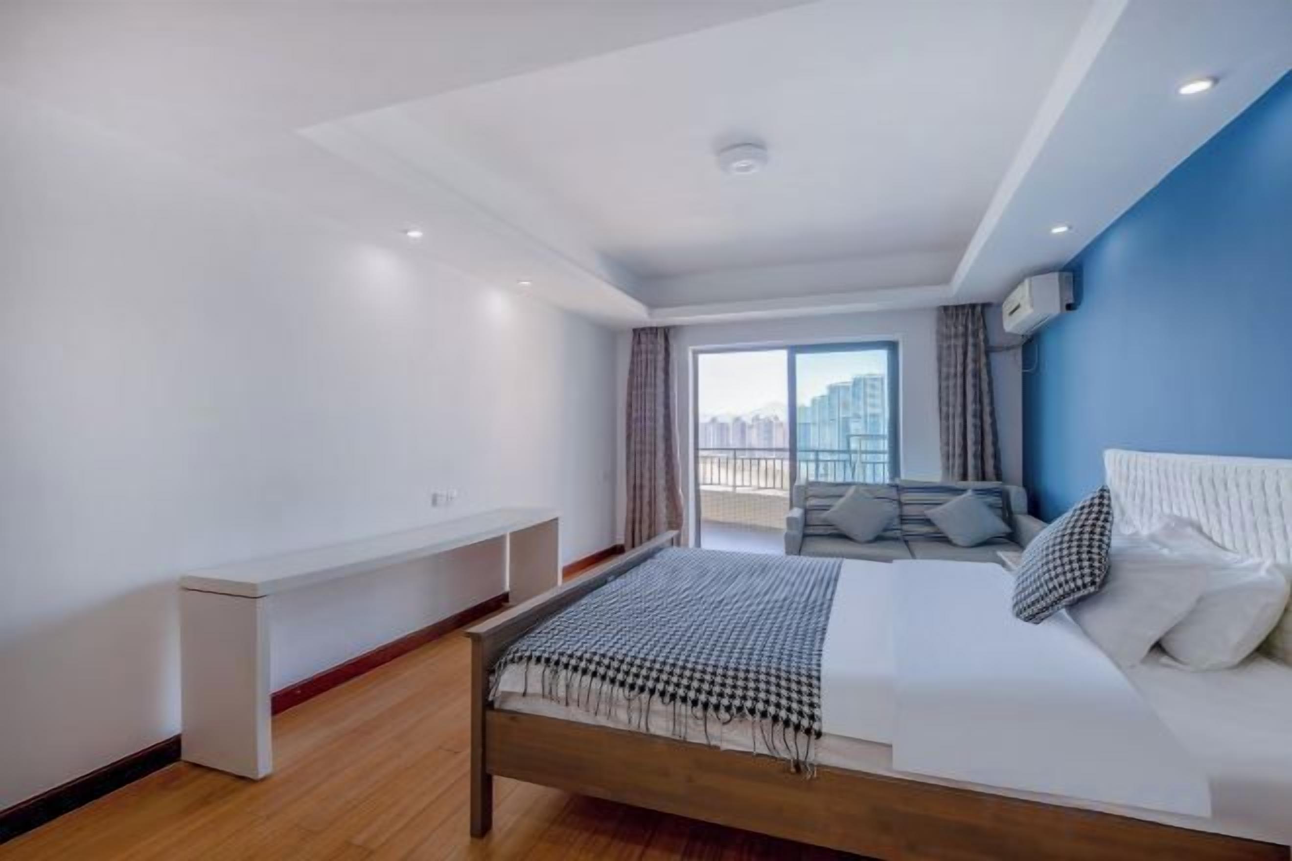A modern hotel room with a bed, a seating area, and a view of the city.