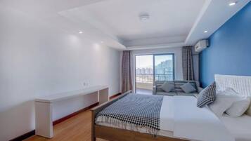 A modern hotel room with a bed, a seating area, and a view of the city.