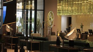 A modern lobby with a green sofa, a large wall clock, and a decorative light fixture. - ASBU Hotel (Tunis)