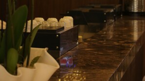 A modern interior with a wooden wall, a marble counter, and hanging pendant lights. - ASBU Hotel (Tunis)