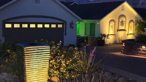 A modern house with a garage, a well-lit entrance, and a mountain backdrop. - Songbirds N Serenity (Oro Valley)