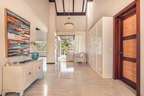 Enter a serene hallway leading to a conservatory with a view of palm trees.