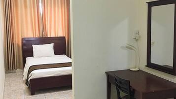 Una habitación de hotel con cama, escritorio, silla, espejo y aire acondicionado.