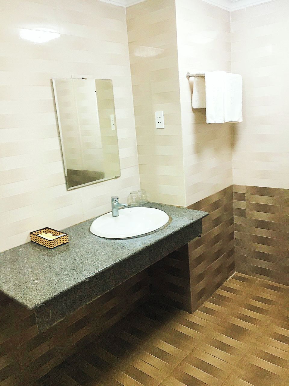 A bathroom with a granite countertop sink, a mirror, and a towel rack.