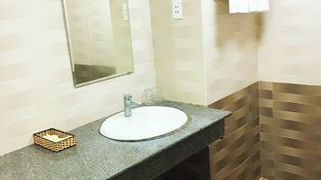 A bathroom with a granite countertop sink, a mirror, and a towel rack.