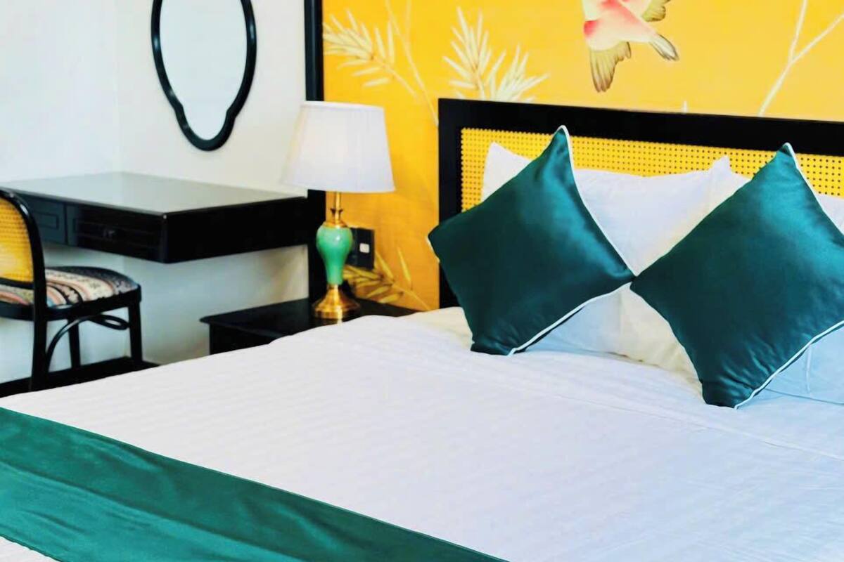 Een hotelkamer met een bed, bureau, stoel en nachtkastje met lamp.