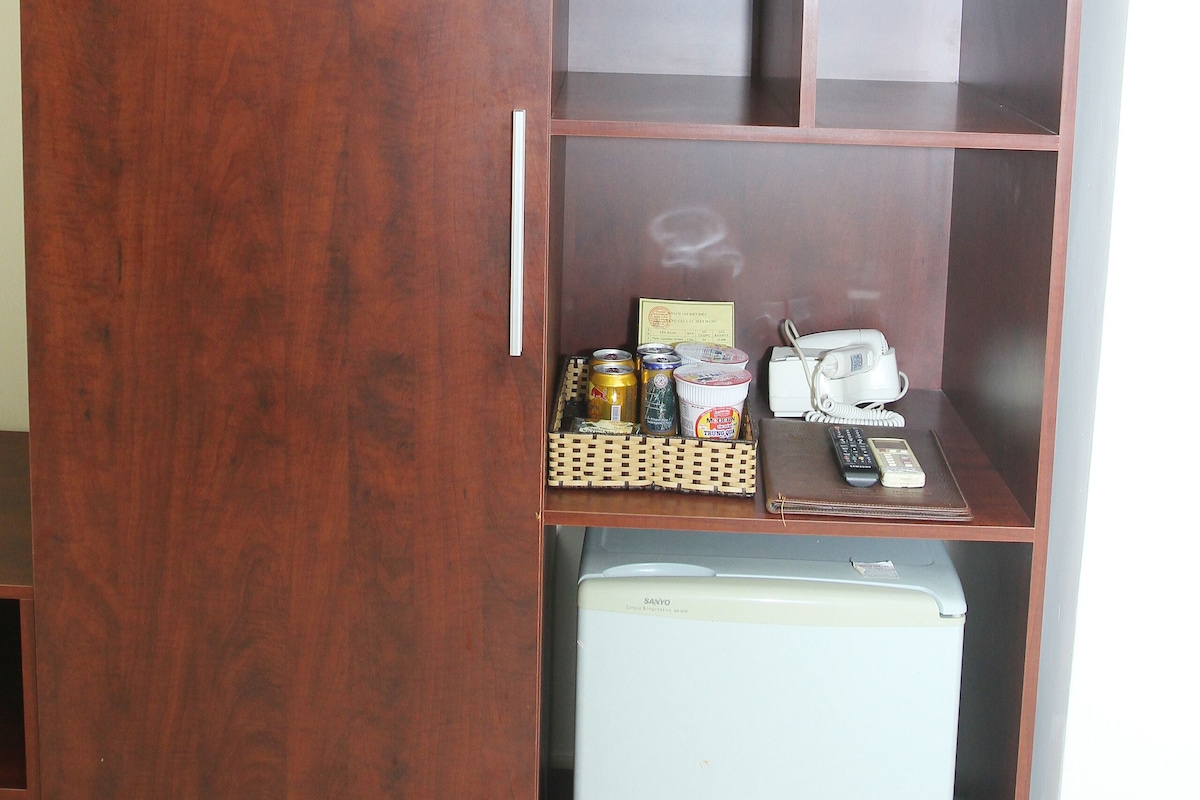Une armoire en bois avec plusieurs compartiments, un petit réfrigérateur et quelques objets sur l’étagère supérieure.