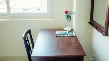 Una mesa de madera con una lámpara blanca, un florero con flores y una revista.