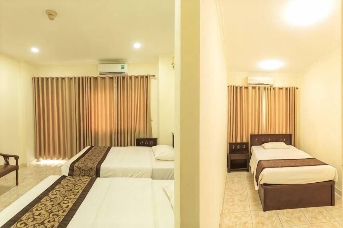 Een hotelkamer met twee bedden, een bureau, een stoel en een airconditioning.