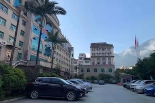 Un estacionamiento con varios autos, un edificio de arquitectura clásica y un cielo despejado.