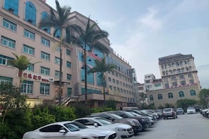 Un estacionamiento con varios coches, un edificio de estilo arquitectónico tradicional y palmeras.