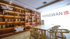 Un moderno vestíbulo de hotel con estanterías de madera, un mostrador de recepción y un comedor con sillas de madera.