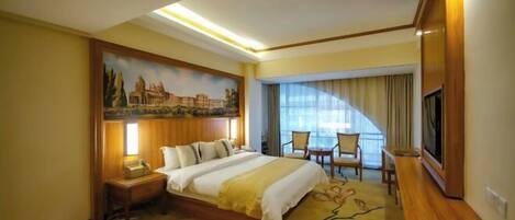 A hotel room with a bed, a desk, a chair, a TV, and a painting on the wall.