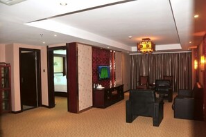 A hotel room with a bed, a television, a seating area with chairs, and a curtain.