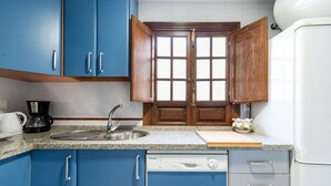A kitchen with blue cabinets, a white dishwasher, and a wooden window with a grid pattern. - San Marcos. 2 bedrooms, 2 bathrooms (Sevilla)
