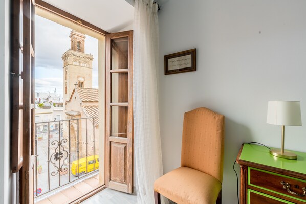 A room with a view of a tower and a yellow car outside.