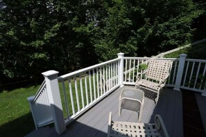 Eine Holzterrasse mit weißen Geländern und zwei Stühlen.