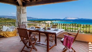 A wooden table set for dining with a view of the sea and mountains. - Apartment "Ida Isuledda 2" with Pool, Garden & Wi-Fi (San Teodoro)