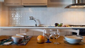 Uma cozinha moderna com painel de azulejos, eletrodomésticos de aço inoxidável e uma área de jantar com mesa de madeira.