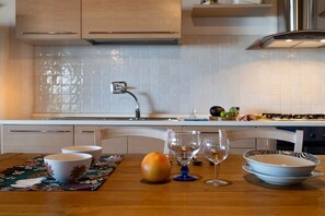 Une cuisine moderne avec un mur recouvert de carreaux, des appareils électroménagers en acier inoxydable et un coin repas doté d’une table en bois.
