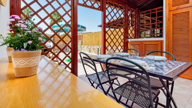 Une table en bois avec des chaises, une plante en pot et une cloison ajourée dans un espace patio.
