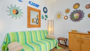 Une pièce avec un canapé à rayures, un meuble en bois et des éléments décoratifs sur les murs, notamment des motifs solaires et un miroir.