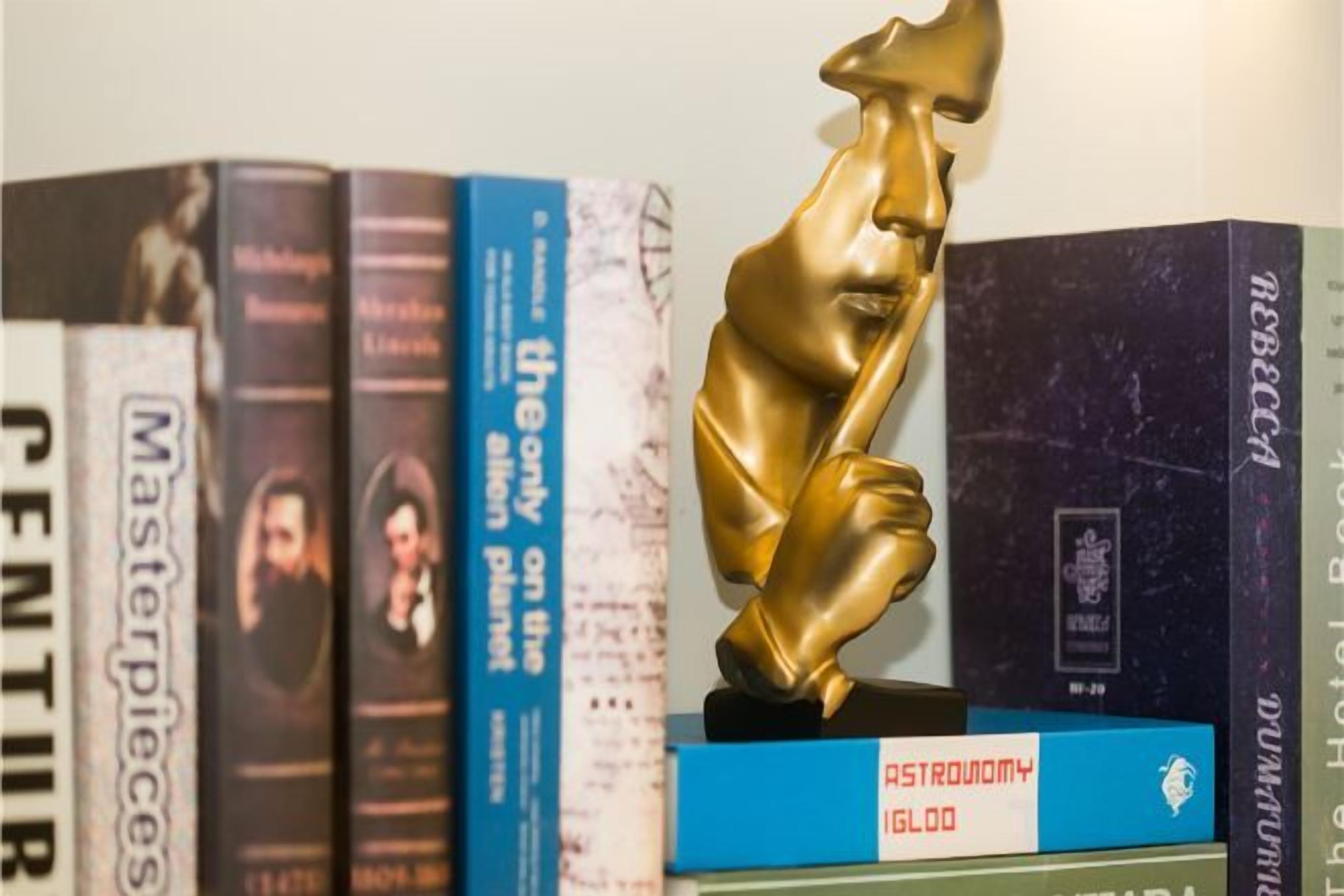 A collection of books with a statuette on top.