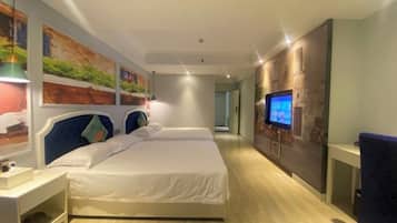 A modern hotel room with a large bed, a TV, and artwork on the walls.