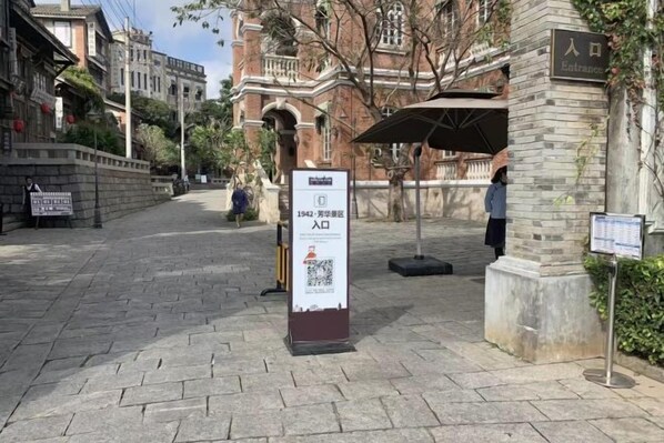 Uma passarela pavimentada que leva à entrada de um edifício, com uma placa indicando o ano de 1942.