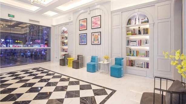 A lobby with a checkered floor, seating areas, bookshelves, and a view of the mall. - Haikou Dream House Hotel (Nansha Road) (Haikou)