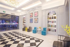 A lobby with a checkered floor, seating areas, bookshelves, and a view of the mall.